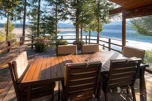 A wooden deck with a table and chairs, overlooking a lake and mountains. - Lakeside (Cle Elum)