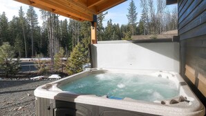 A hot tub under a wooden pergola with a forest view.