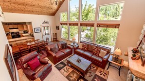 A spacious living area with a high ceiling, large windows, a fireplace, and a cozy seating arrangement.