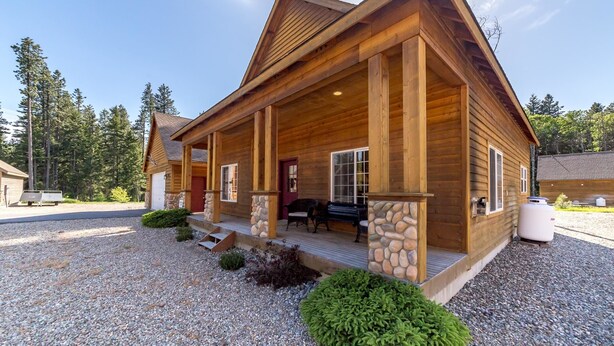 A log cabin with a porch, stone accents, and a gravel driveway. - Wintergreen Chalet (Cle Elum)