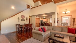 A spacious living room with a wooden staircase, a dining area, and a kitchen in the background. - Wintergreen Lodge (Cle Elum)