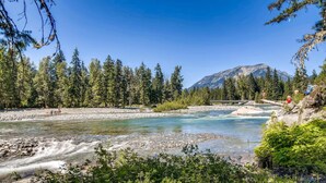 A river flowing through a forest with a mountain in the background. - Wintergreen Lodge (Cle Elum)