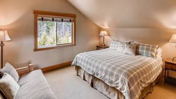 A bedroom with a large bed, two bedside tables, a window, and a radiator.