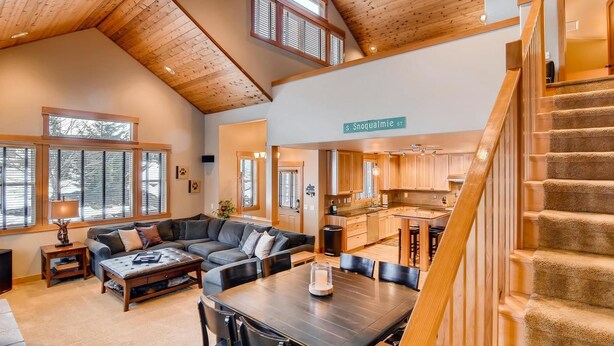 A spacious living area with a large sofa, a dining table, and a kitchen in the background. - Whispering Pines (Cle Elum)