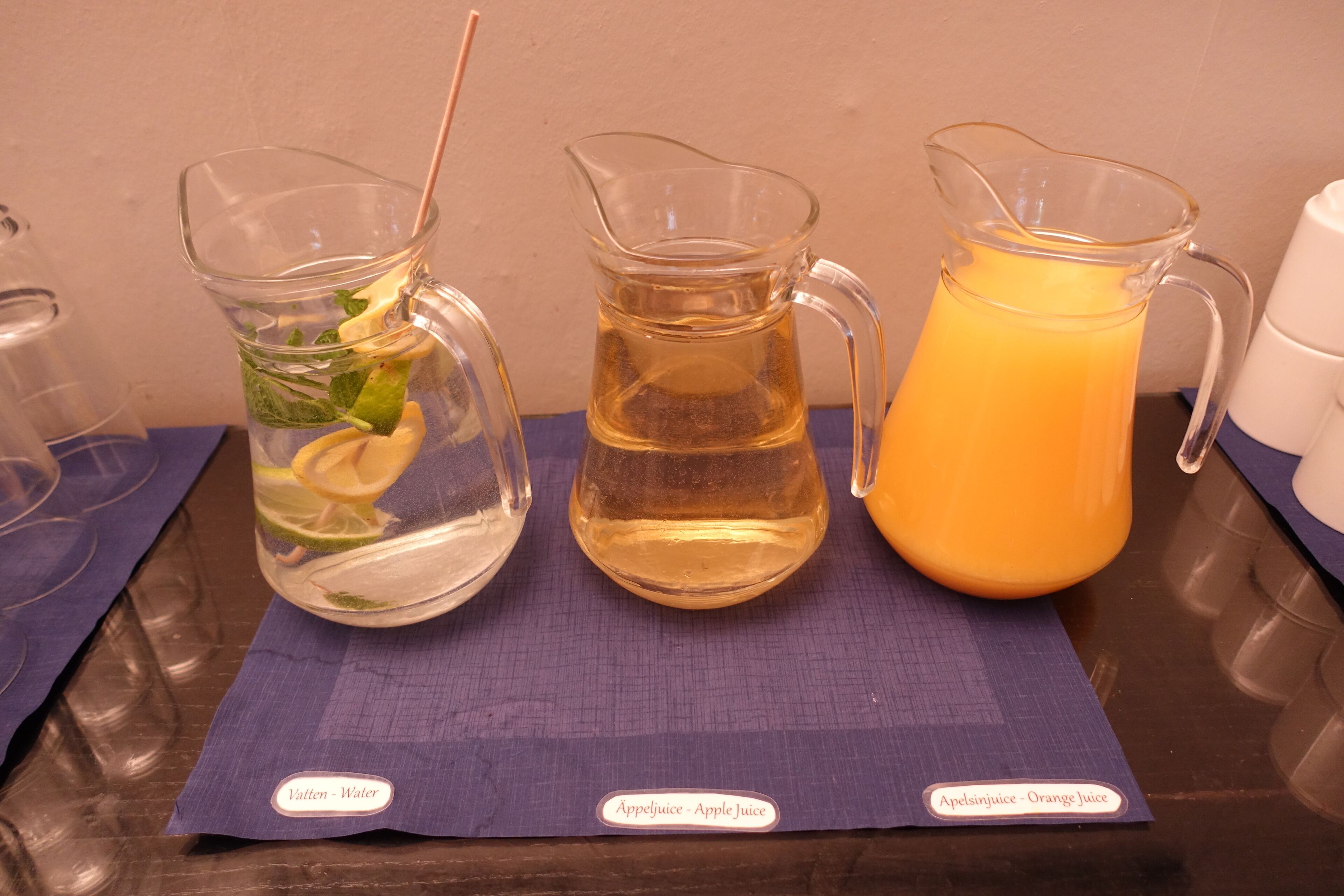 Tres jarras de bebidas sobre una mesa con etiquetas.