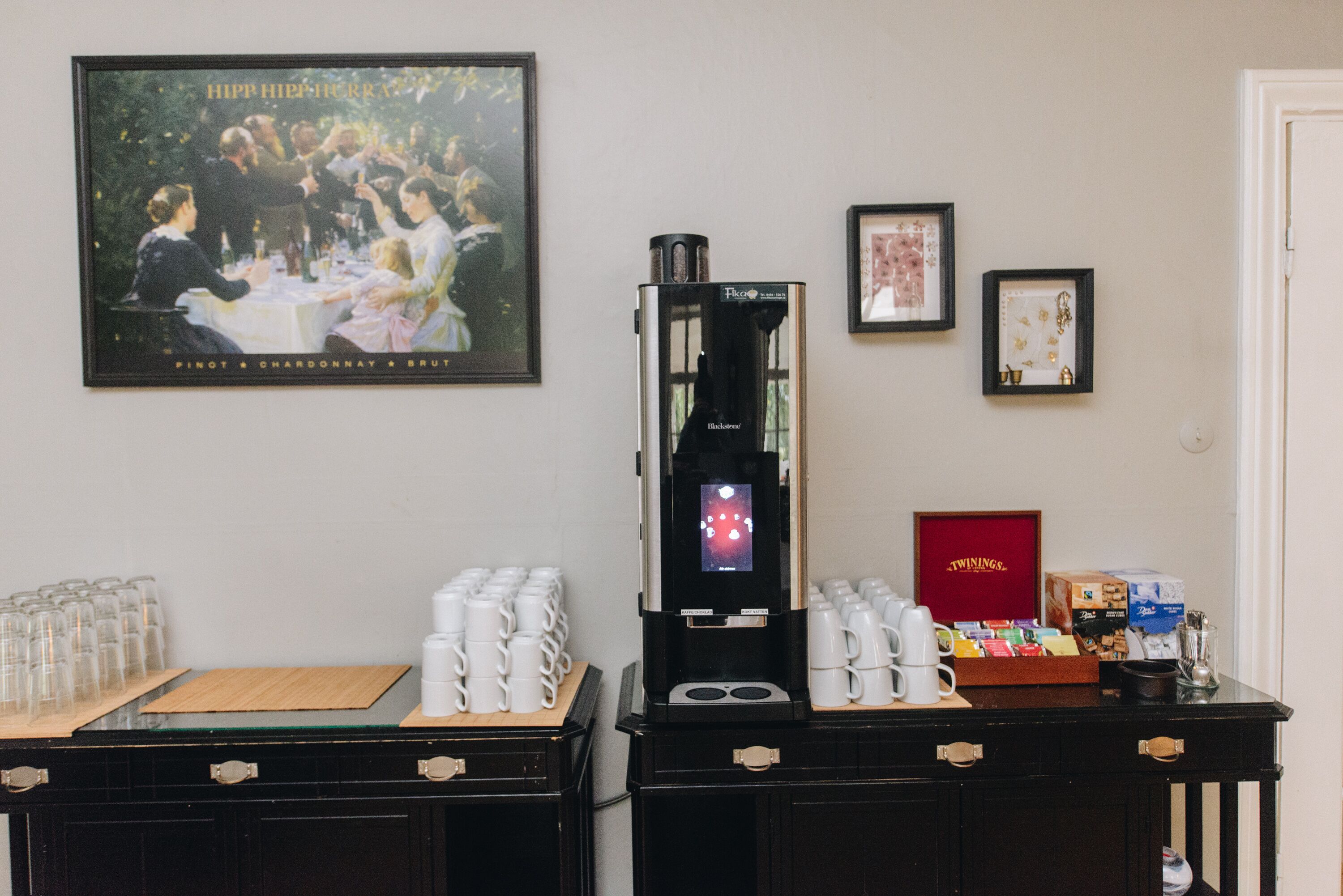 Un coin café équipé d’une machine à café, de tasses et d’une boîte de thé Twinings.