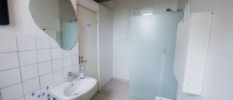 Baño con lavamanos, espejo y ducha.