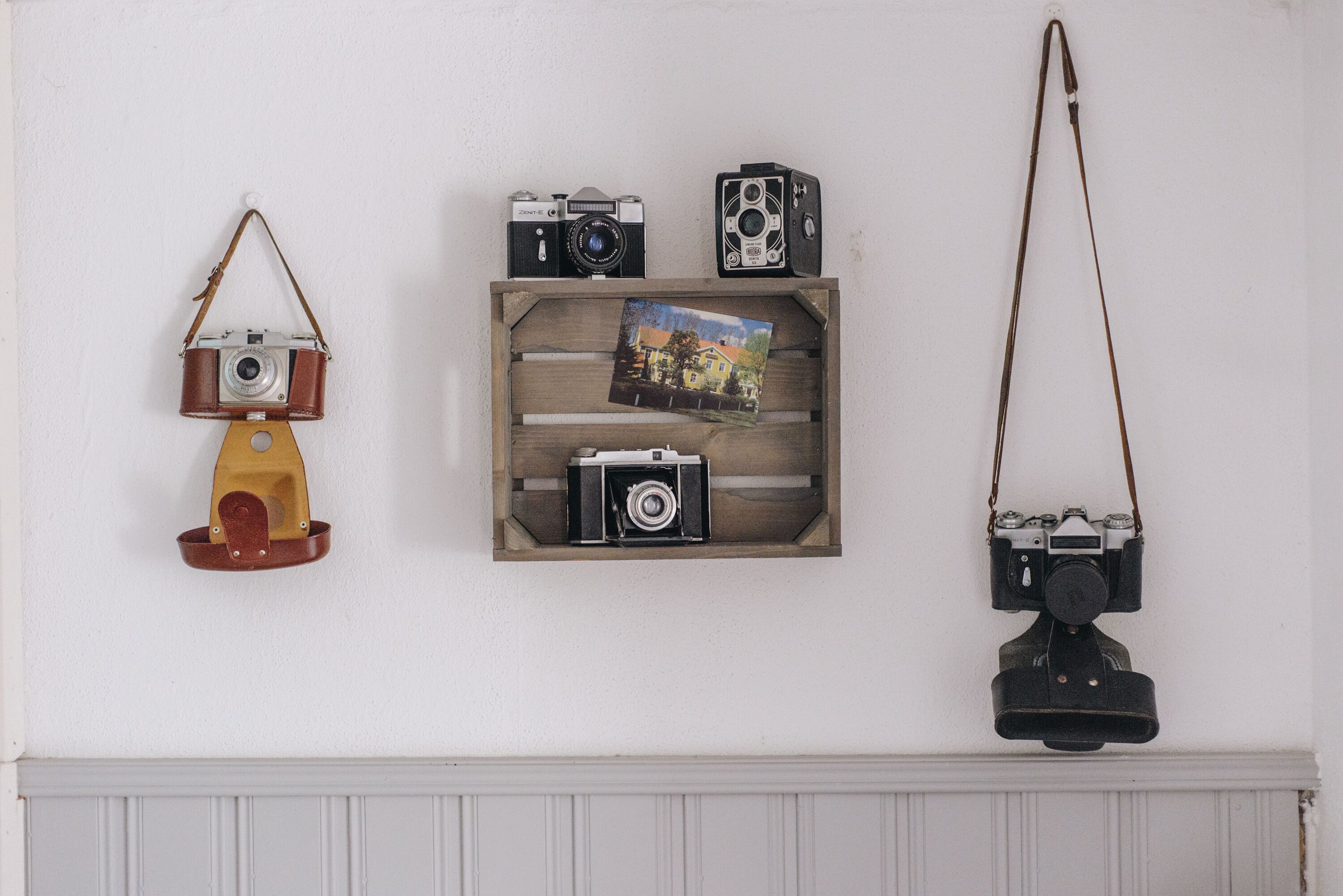 A wall with three vintage cameras and a photo frame.