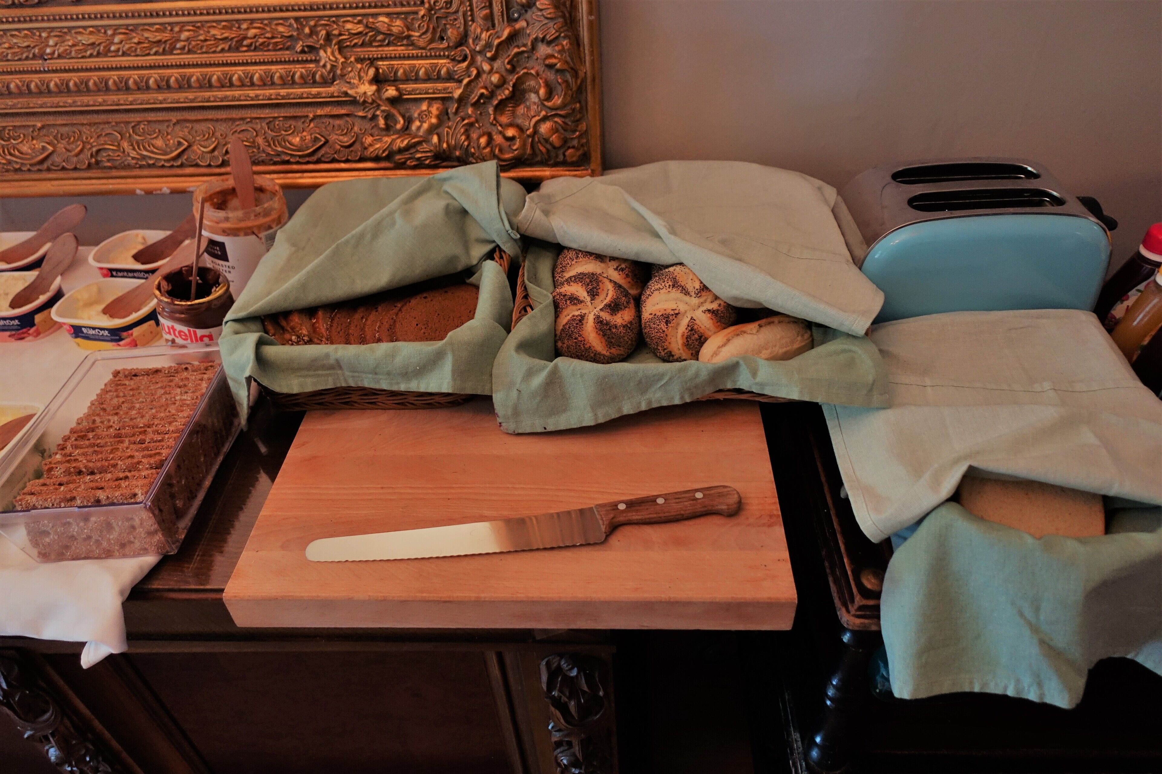 A kitchen counter with a loaf of bread, a jar of Nutella, and a knife.