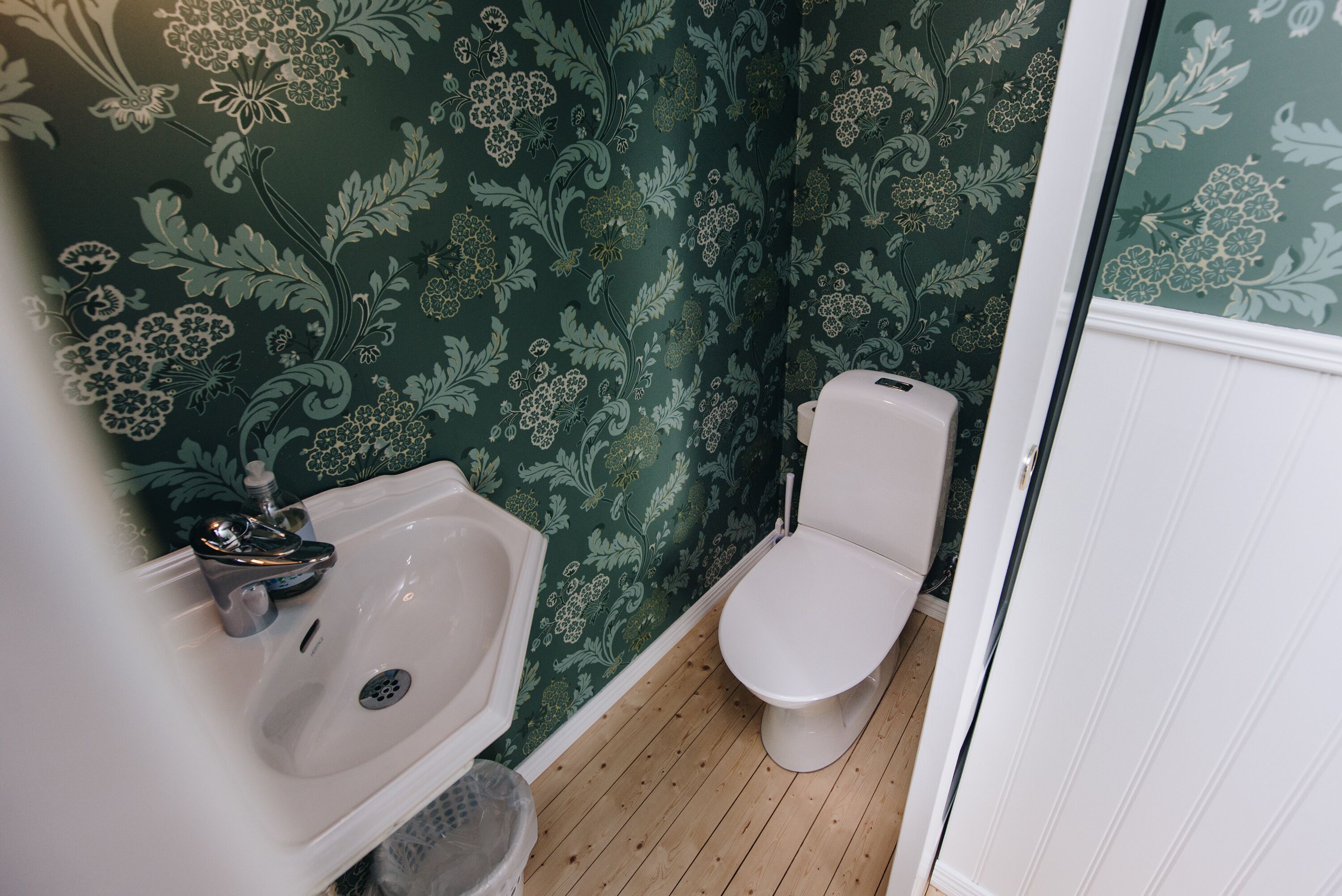 Un baño con lavamanos, inodoro y suelo de madera.