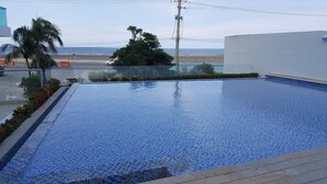 A swimming pool with blue mosaic tiles, surrounded by a low wall and a row of red flowers. - Apartamento Mistral Cielo Mar (Cartagena)