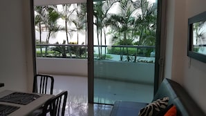A room with a sliding glass door leading to a balcony with palm trees. - Apartamento Mistral Cielo Mar (Cartagena)