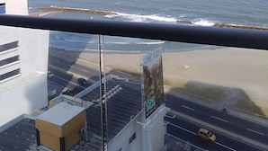 A view from a balcony overlooking a beach with a clear sky. - Apartamentos vista mar Milano (Cartagena)