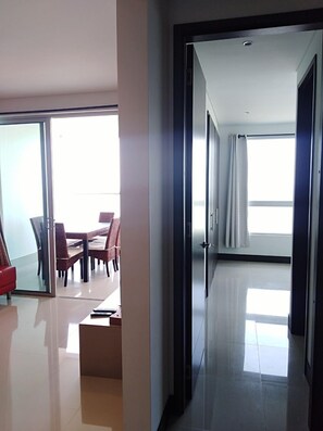 A modern hotel room with a glass door leading to a dining area with a table and chairs.