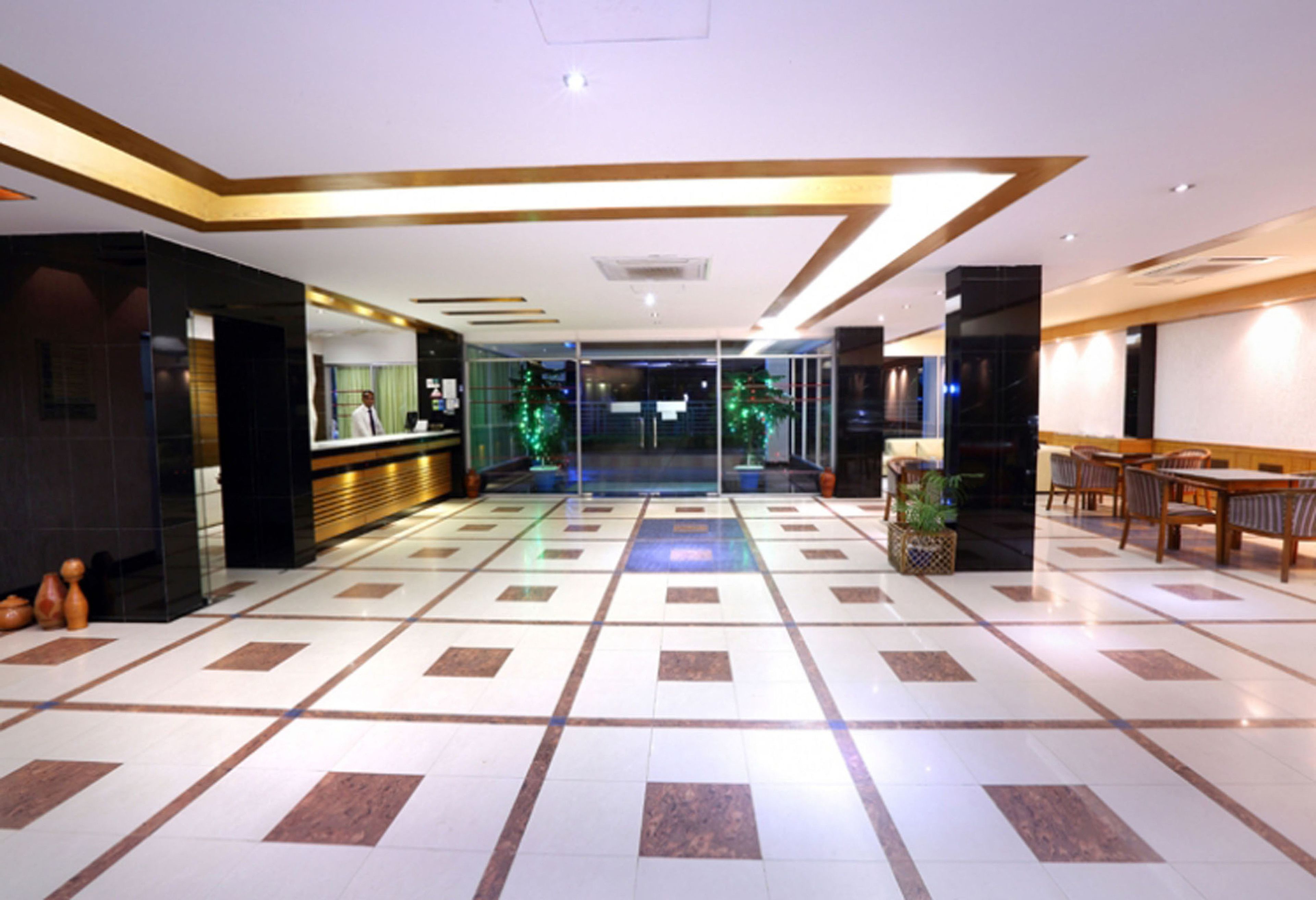 A hotel lobby with a check-in counter, seating area, and a tiled floor.
