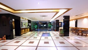 A hotel lobby with a check-in counter, seating area, and a tiled floor. - Uni Resort (Cox's Bazar)