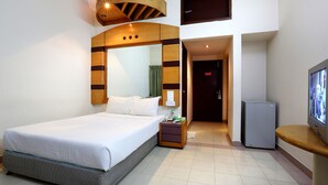 A hotel room with a bed, nightstand, TV, and a small refrigerator. - Uni Resort (Cox's Bazar)