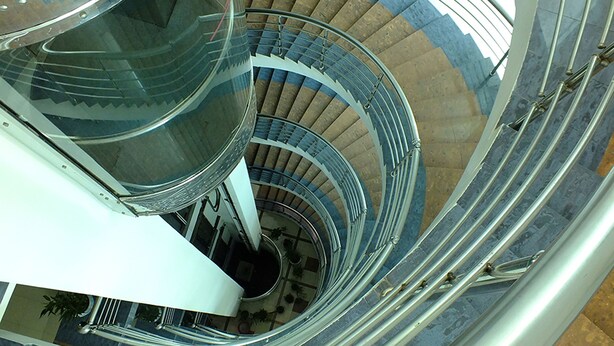 A spiral staircase with a glass enclosure and metal railings. - Uni Resort (Cox's Bazar)