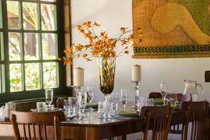 A dining table set with clear glassware, a vase with orange flowers, and candles.