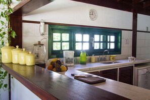A kitchen with a wooden countertop, a coffee maker, a kettle, and a fruit bowl.