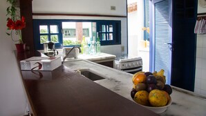 A kitchen with a sink, stove, and a bowl of fruit on the counter. - Homestay Búzios (Búzios)