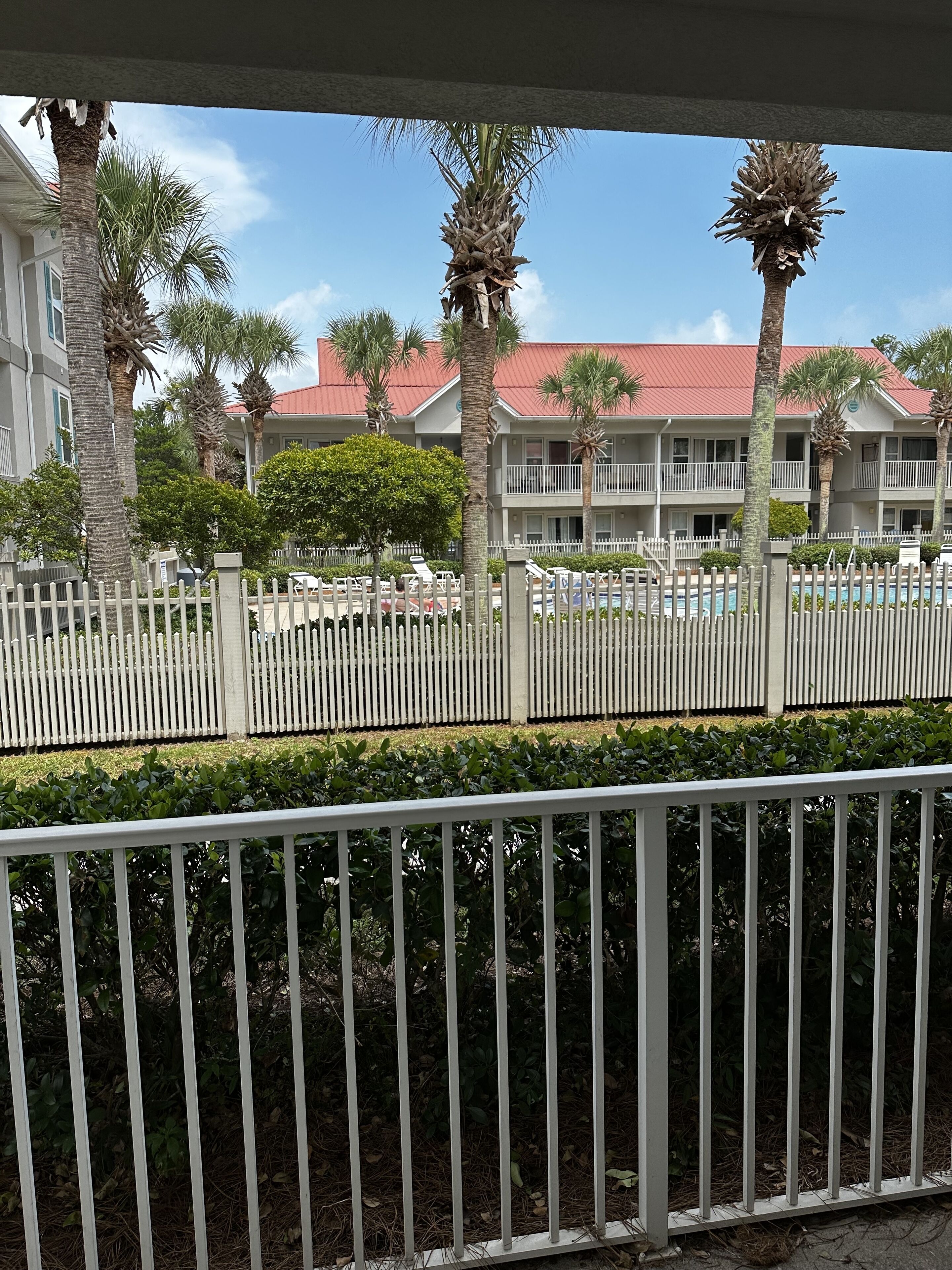 A hotel with a red roof, white balconies, and a white fence.