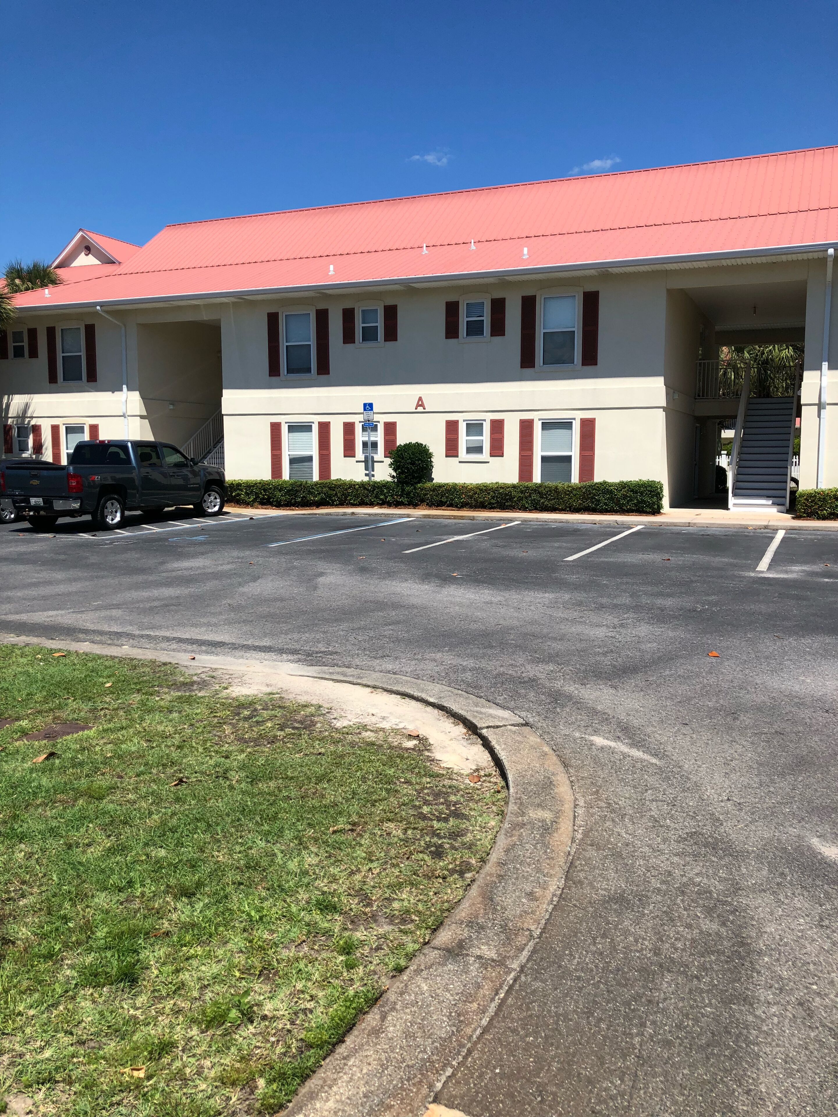 A building with a red roof, a parking lot, and a blue handicap parking sign.