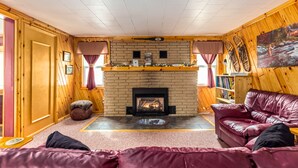 Una habitación acogedora con chimenea, un sofá de cuero y paredes de madera.