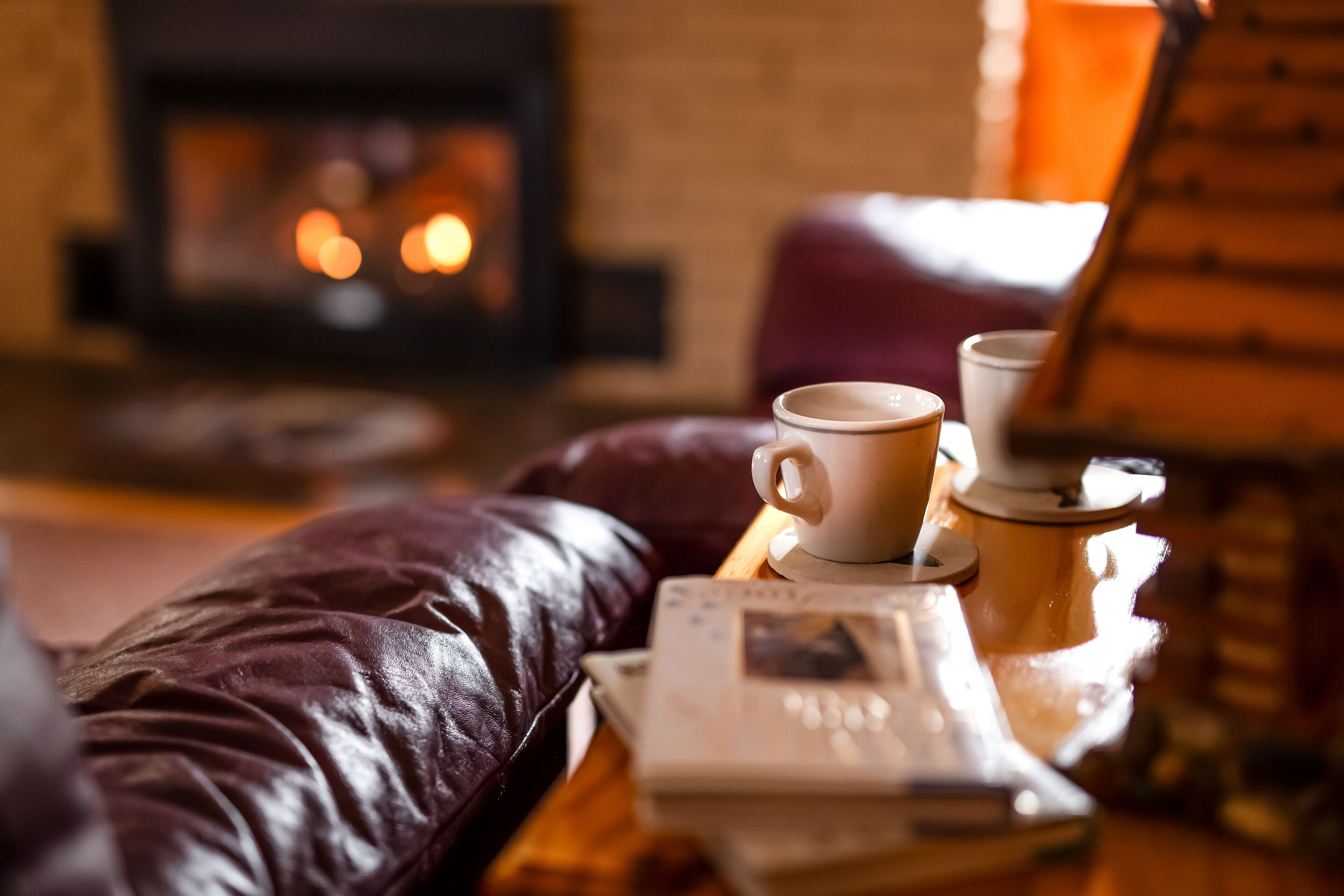 Ein gemütliches Wohnzimmer mit einer Ledersofa, einem Holztisch und einem Kamin im Hintergrund.