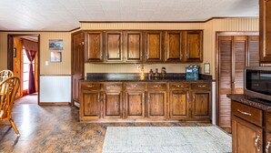 Una cocina con gabinetes de madera, encimera de granito y microondas integrado.