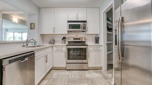 Una cocina moderna con armarios blancos, electrodomésticos de acero inoxidable y lavavajillas.