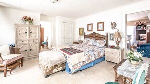 Quarto com uma cama grande, cômoda, cadeira e mesa com um vaso de flores.