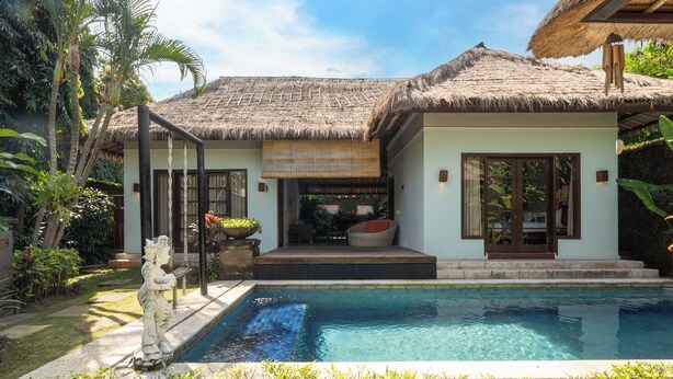 A resort with a pool, a thatched-roof building, and tropical vegetation. - Kecapi Villa Seminyak (Seminyak)