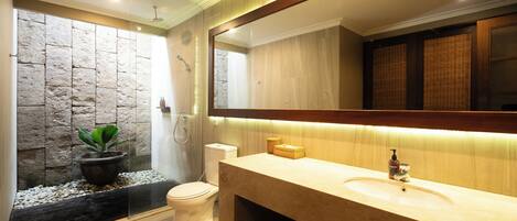A modern bathroom with a stone accent wall, a large mirror, a sink, and a shower.
