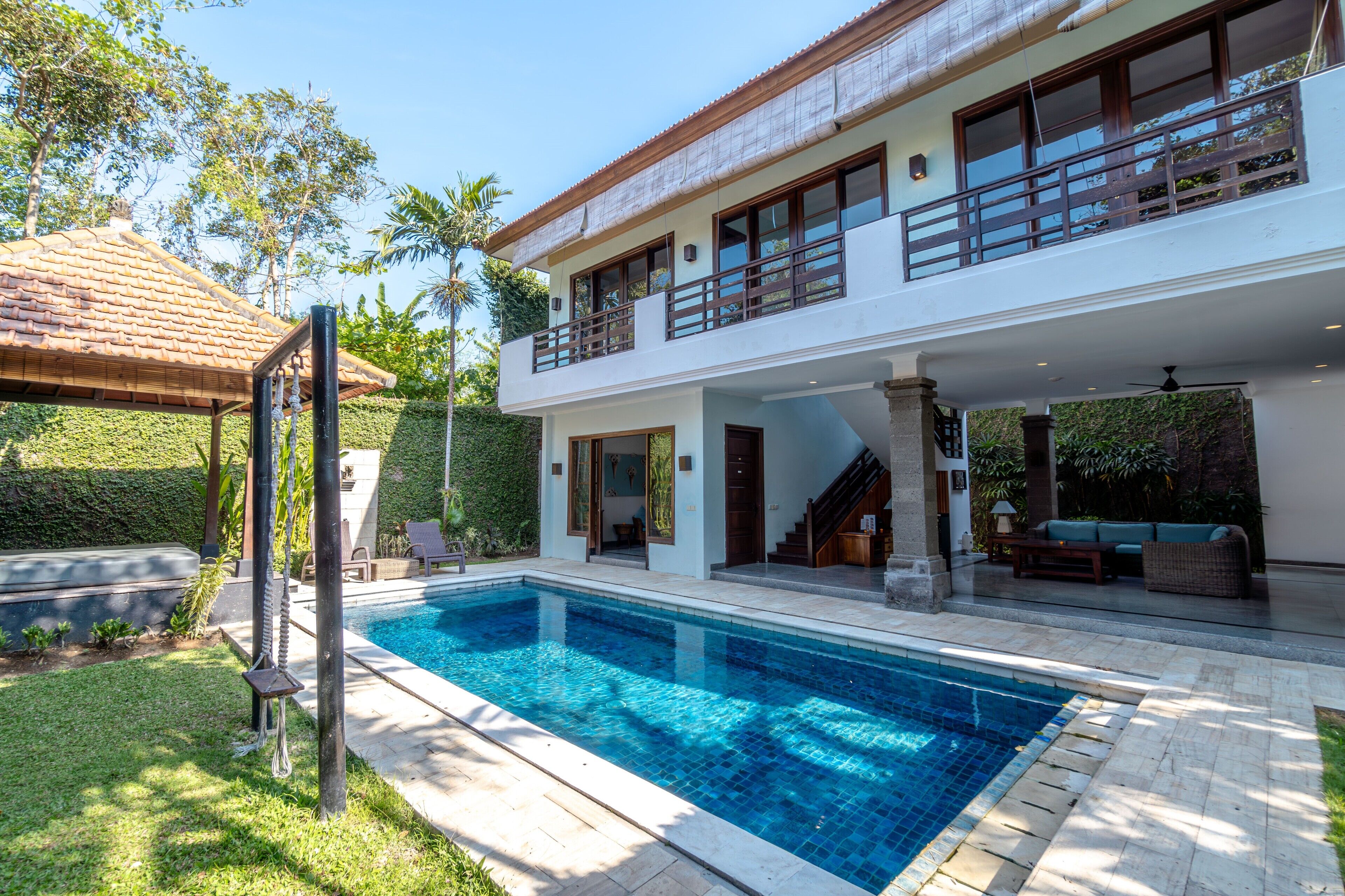 Ein zweigeschossiges Haus mit Swimmingpool, überdachter Terrasse und einer Treppe, die zum Obergeschoss führt.