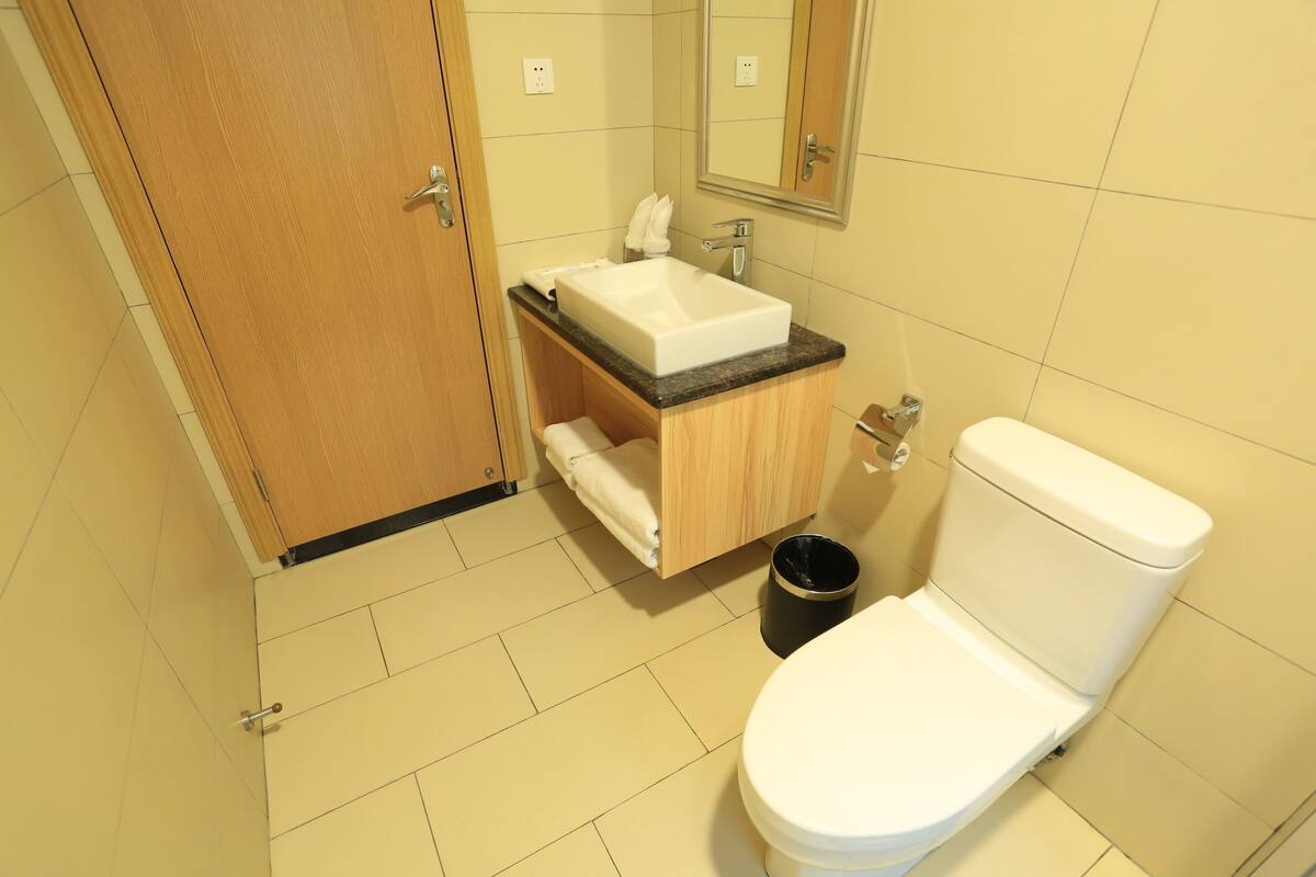 A bathroom with a wooden cabinet, a white sink, a mirror, and a toilet.