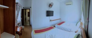 A room with two beds, a TV, a fan, and a desk. - Phan Van Hotel (Da Nang)