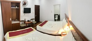 A hotel room with two beds, a wooden wardrobe, a television, a desk with a chair, and a bathroom with a mirror and toilet. - Phan Van Hotel (Da Nang)