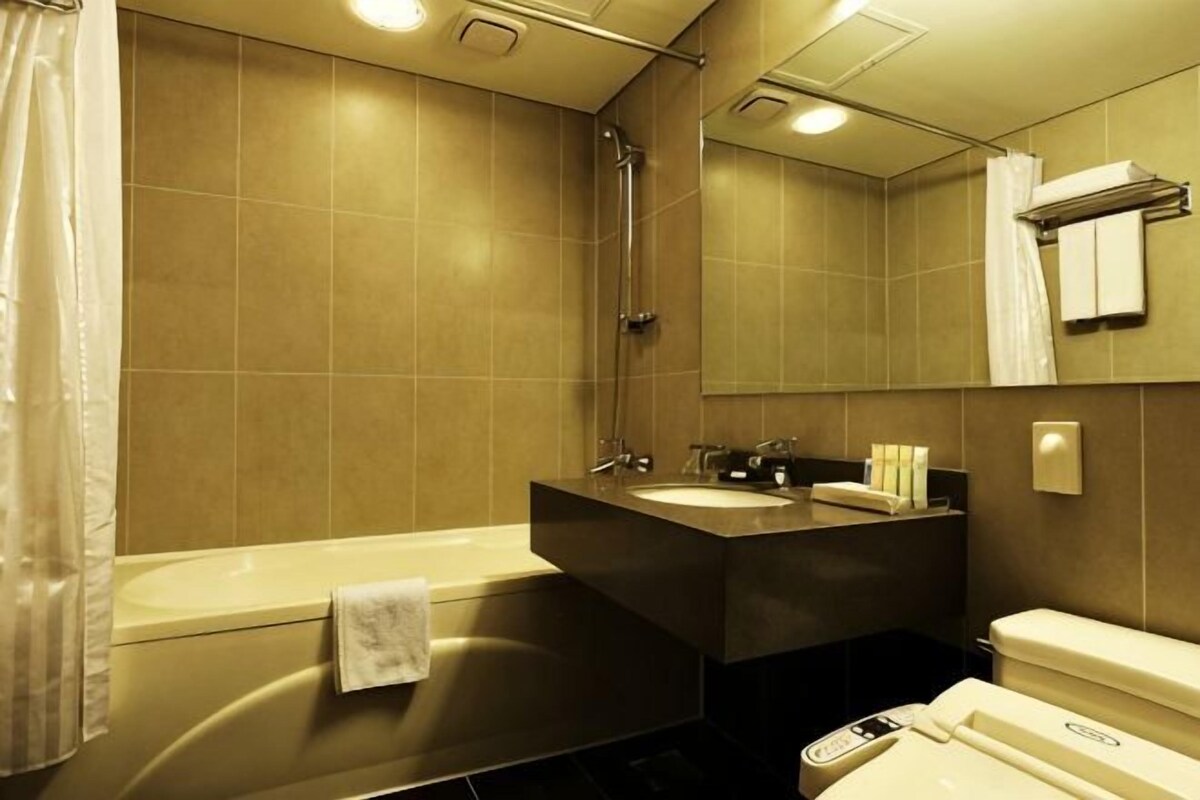 A bathroom with a bathtub, two sinks, a toilet, and a mirror.