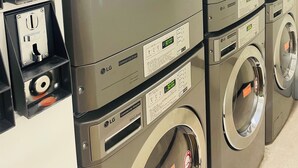 Una hilera de lavadoras comerciales LG con paneles de control y opción de motor directo.