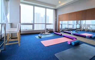 A spacious room with large windows, a yoga mat, a chair, and exercise equipment.
