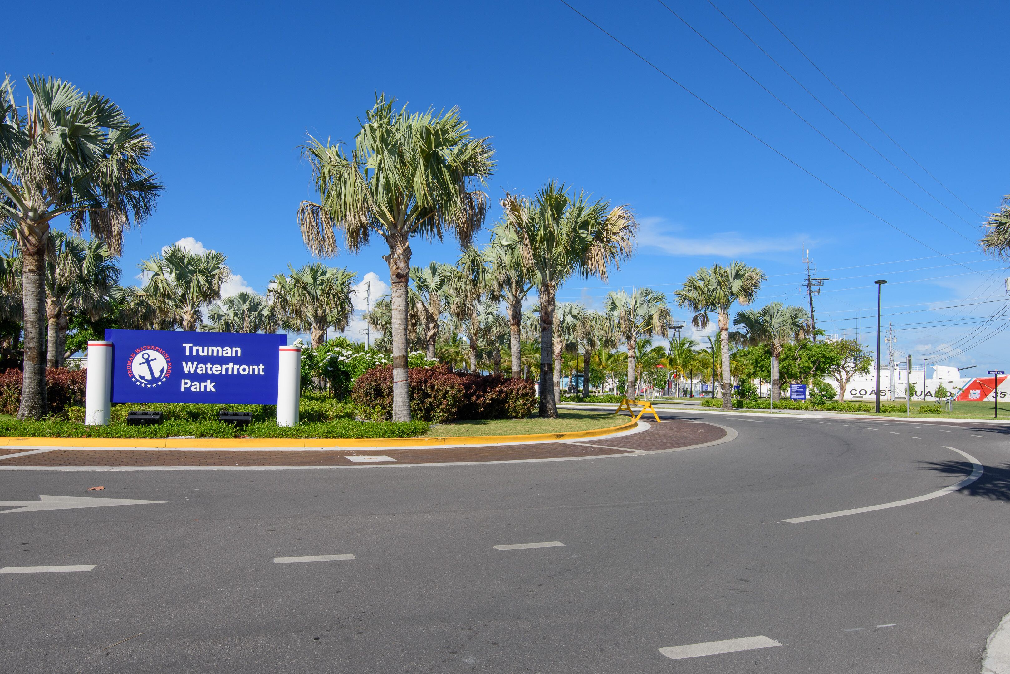 A road leading to Truman Waterfront Park with palm trees and a clear sky.