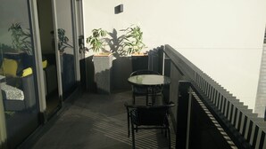 A balcony with a table and chairs, potted plants, and a staircase. - Camberwell Holiday Apartment (Camberwell)