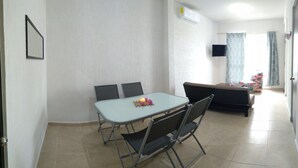 En matplats med ett bord och stolar, en soffa och en tv som hänger på väggen.
