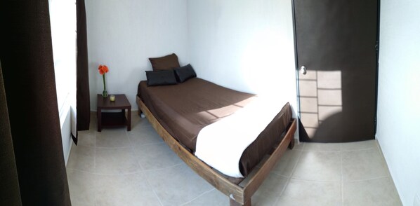 A bedroom with a wooden bed, a nightstand with a vase of flowers, and a door with a view of the outside.