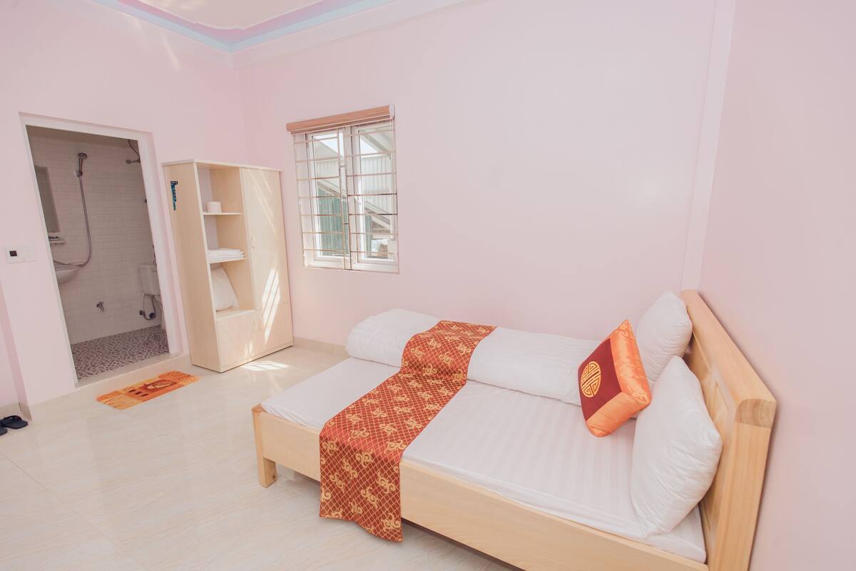 A bedroom with a bed, a window, a wardrobe, and a shower area.