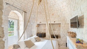 A rustic room with a bed, a fireplace, and a stone wall.