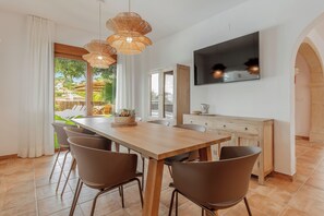 Un espace repas moderne avec une table en bois, des chaises marron et un téléviseur fixé au mur.