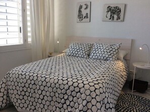 Una camera da letto con un letto con copriletto a motivi geometrici, un comodino con una lampada e due opere d'arte a parete raffiguranti animali.