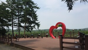 A park with a heart-shaped sign, benches, and a wooden fence.